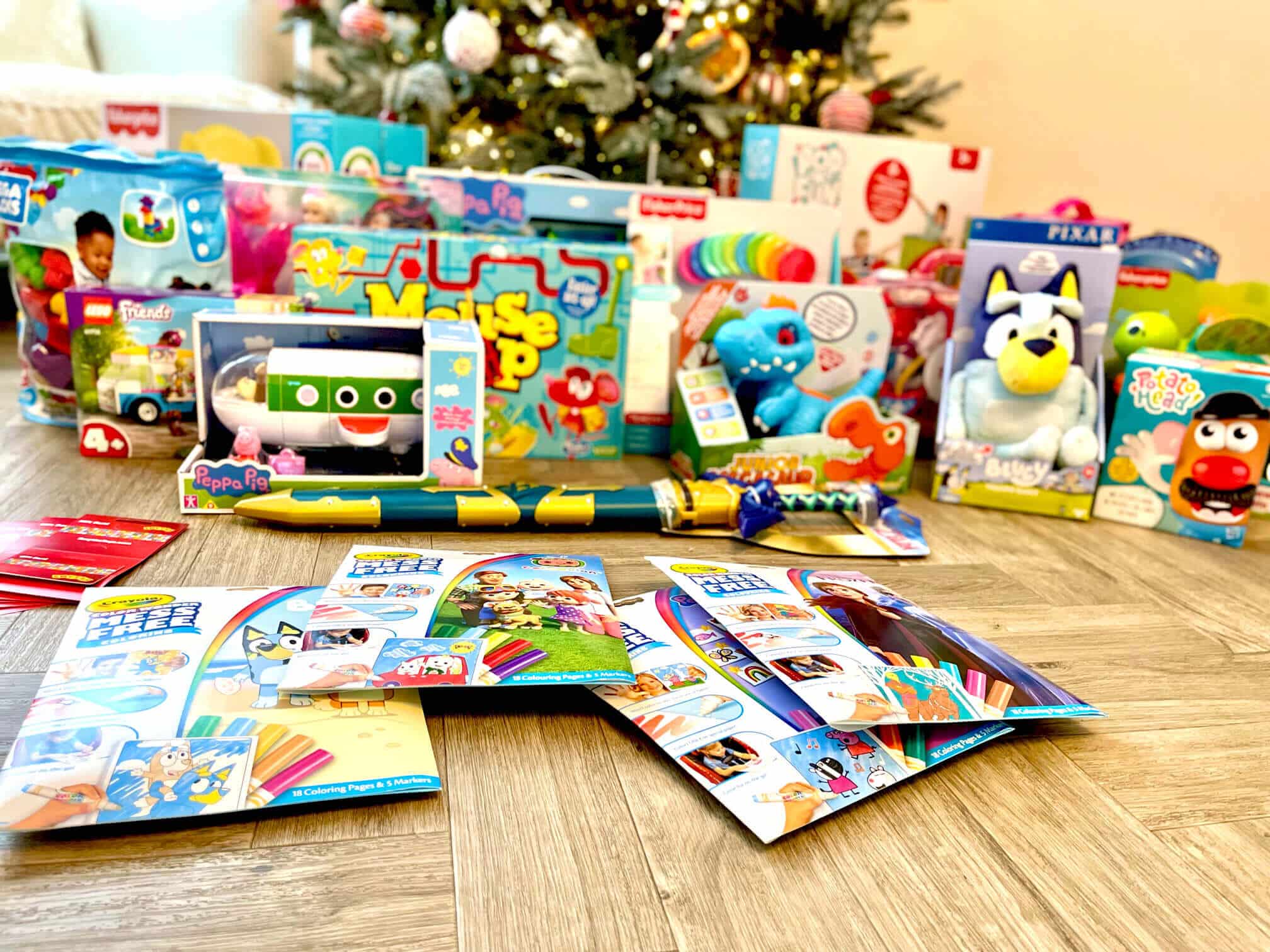 A collection of toys and books near a Christmas tree.