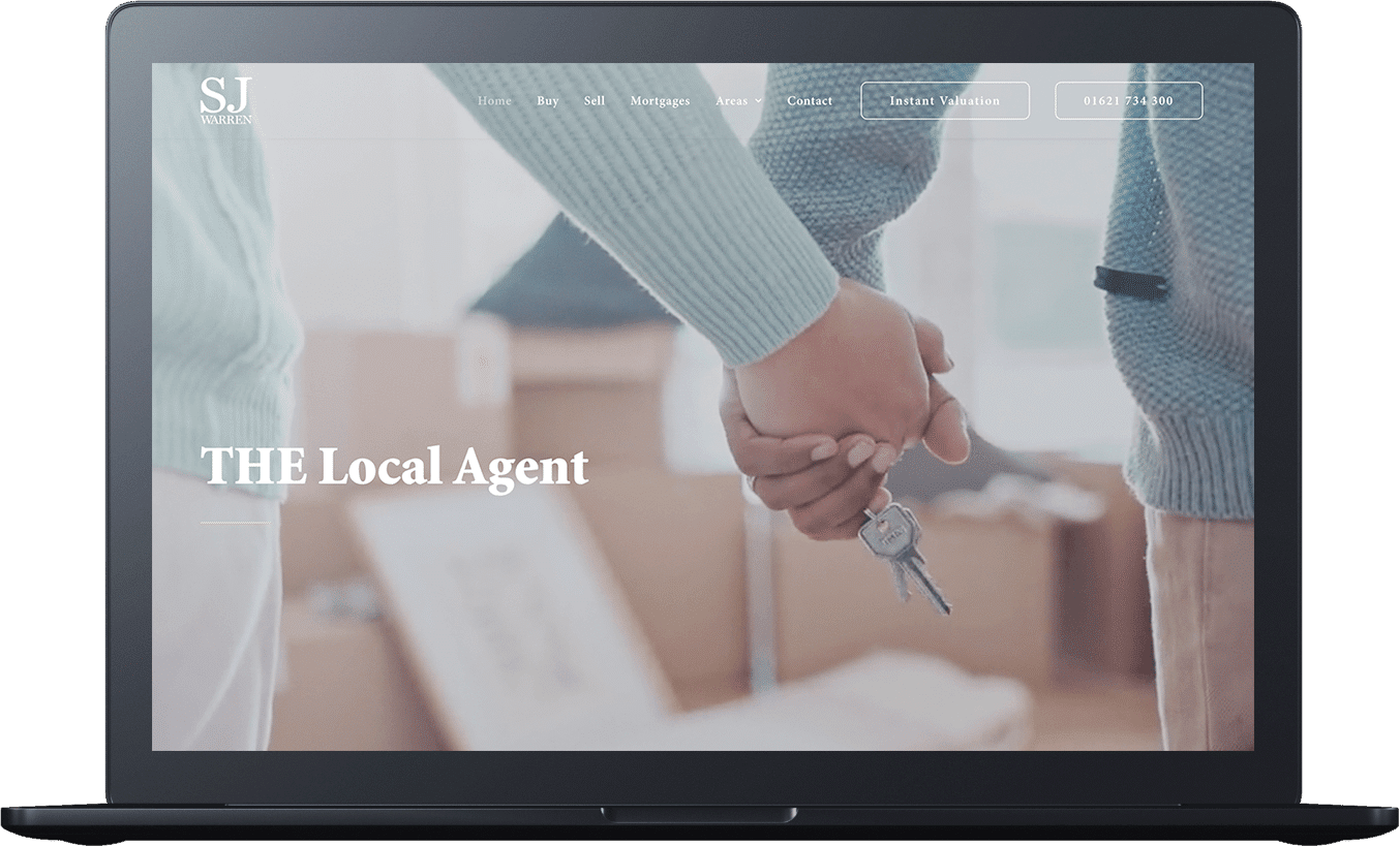 Laptop screen displaying a real estate website with two people holding hands and keys. House moving boxes are visible in the background. Text on the screen includes