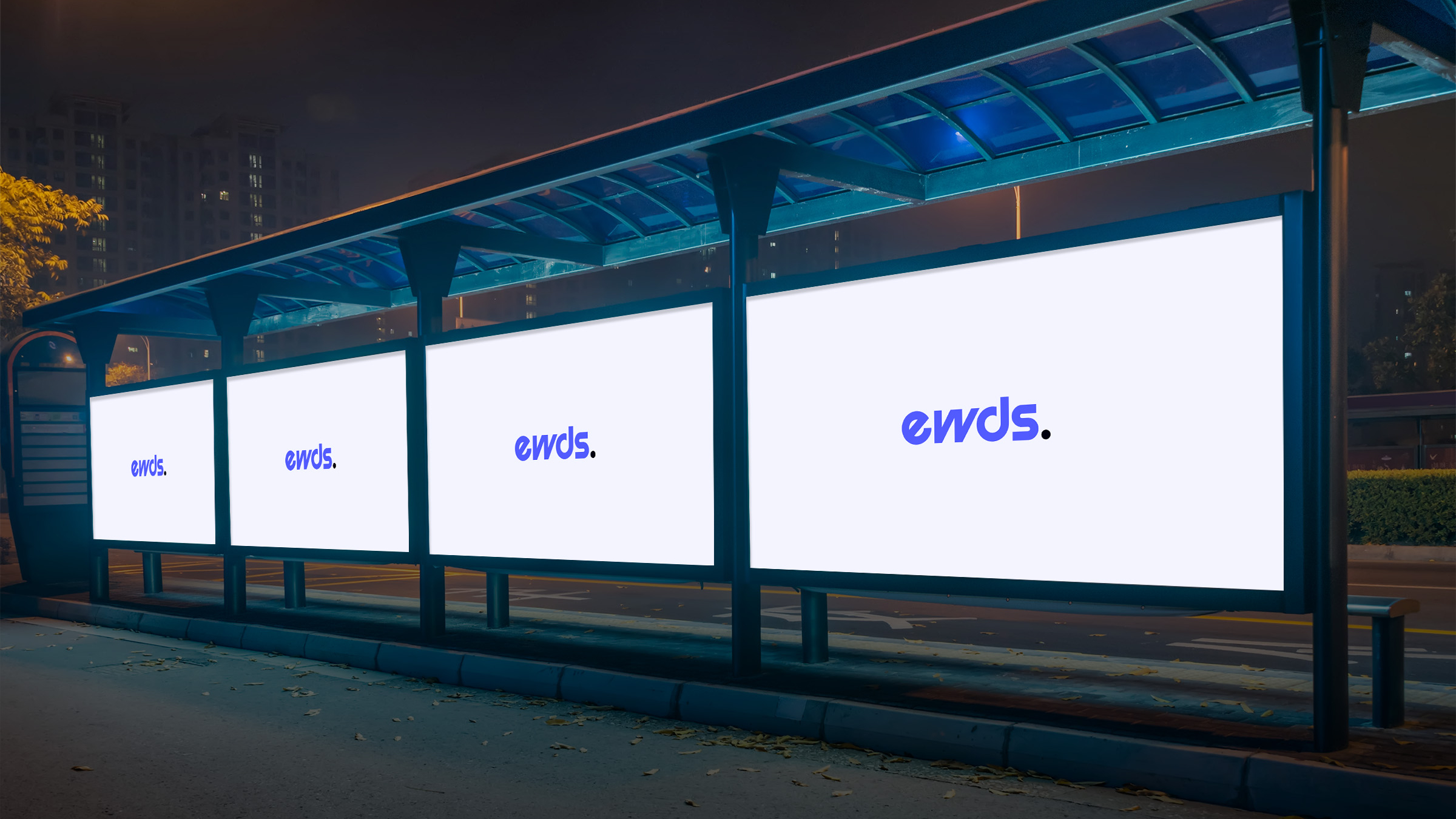 A bus stop at night displaying three illuminated billboards with the word 