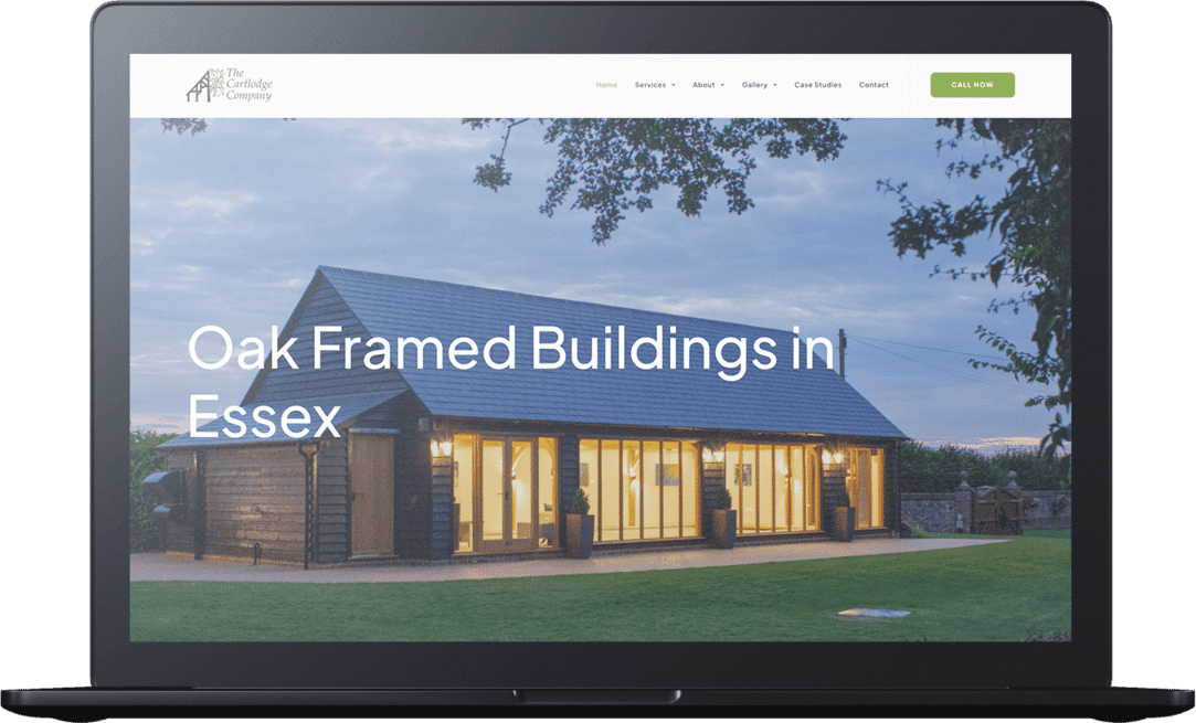 A laptop displays a website featuring a modern oak-framed building with large windows and exterior lighting, titled “Oak Framed Buildings in Essex” by a leading cart lodge company.
