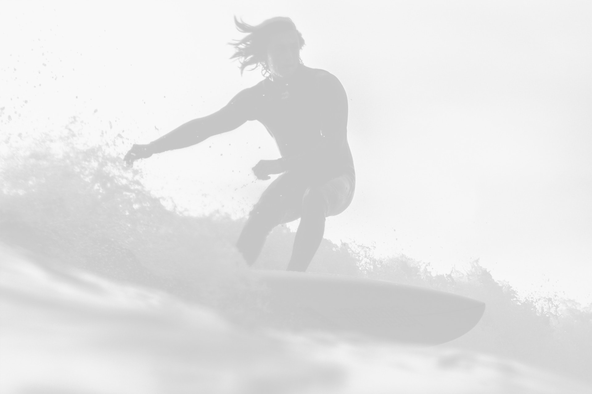 A person surfing on a wave, silhouetted against a bright, misty background.